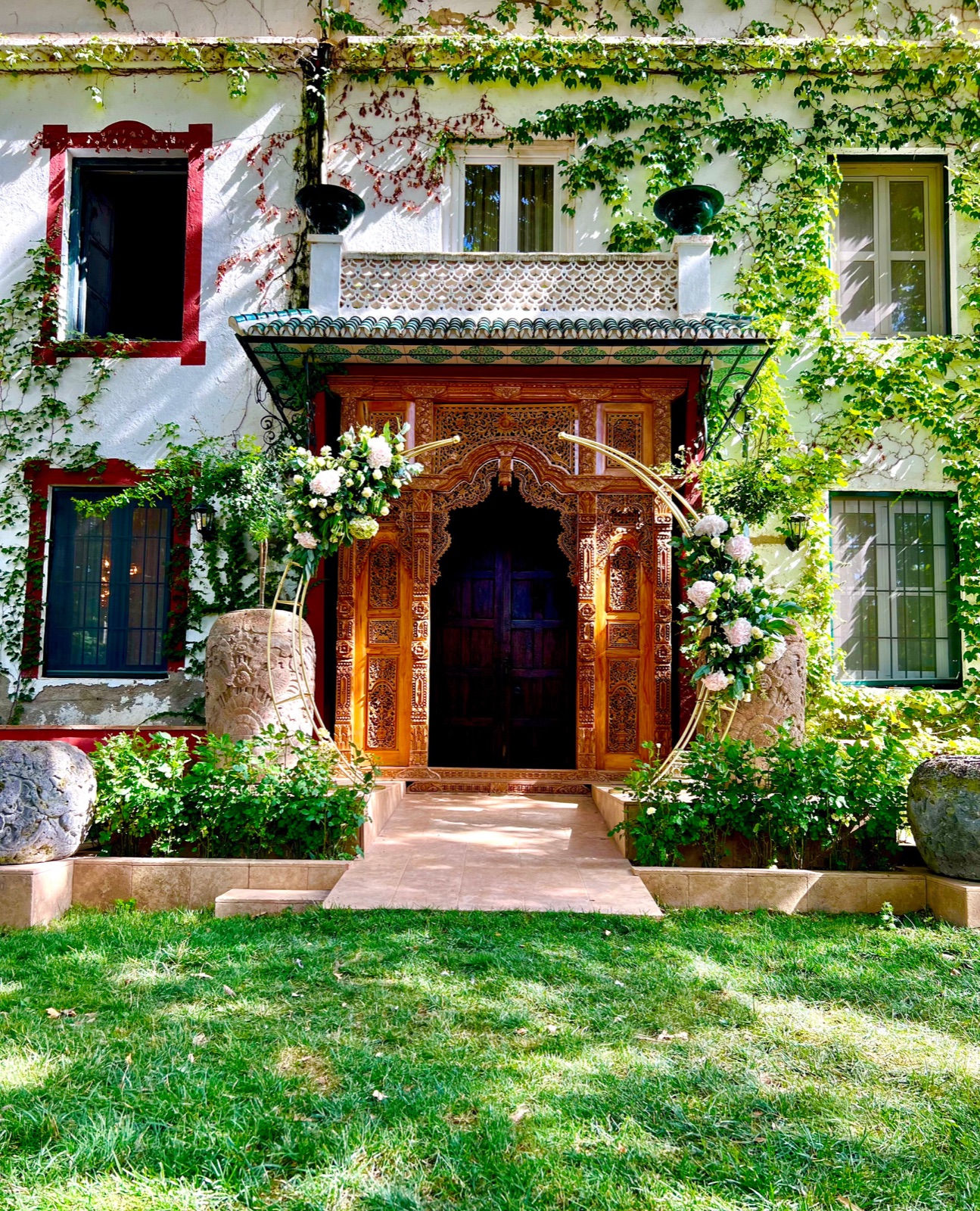 Main entrance of the cortijo, with a carved wooden door and an ivy-covered façade